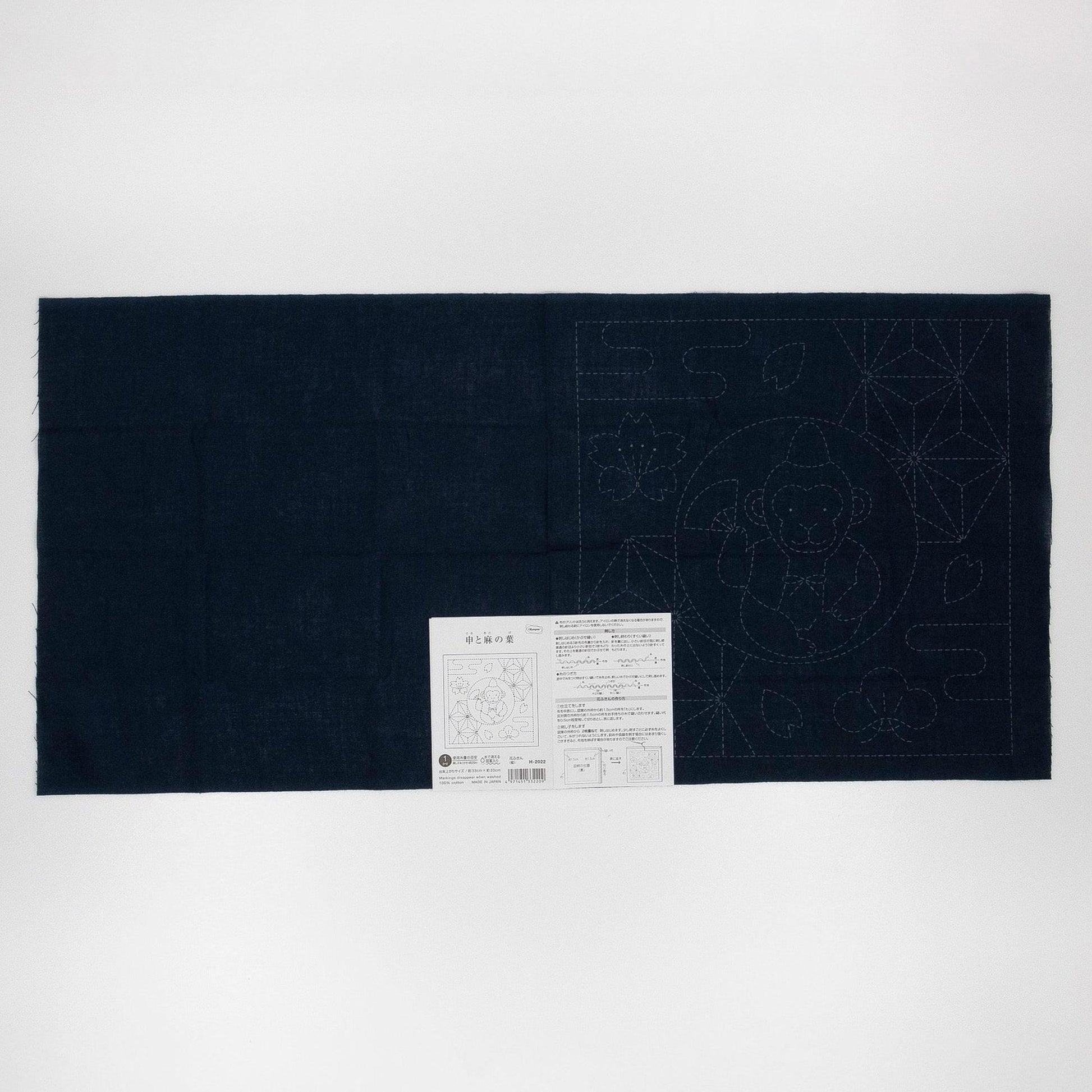 The image is a black fabric with a white label attached to it, which appears to be a sewing or crafting instruction sheet.