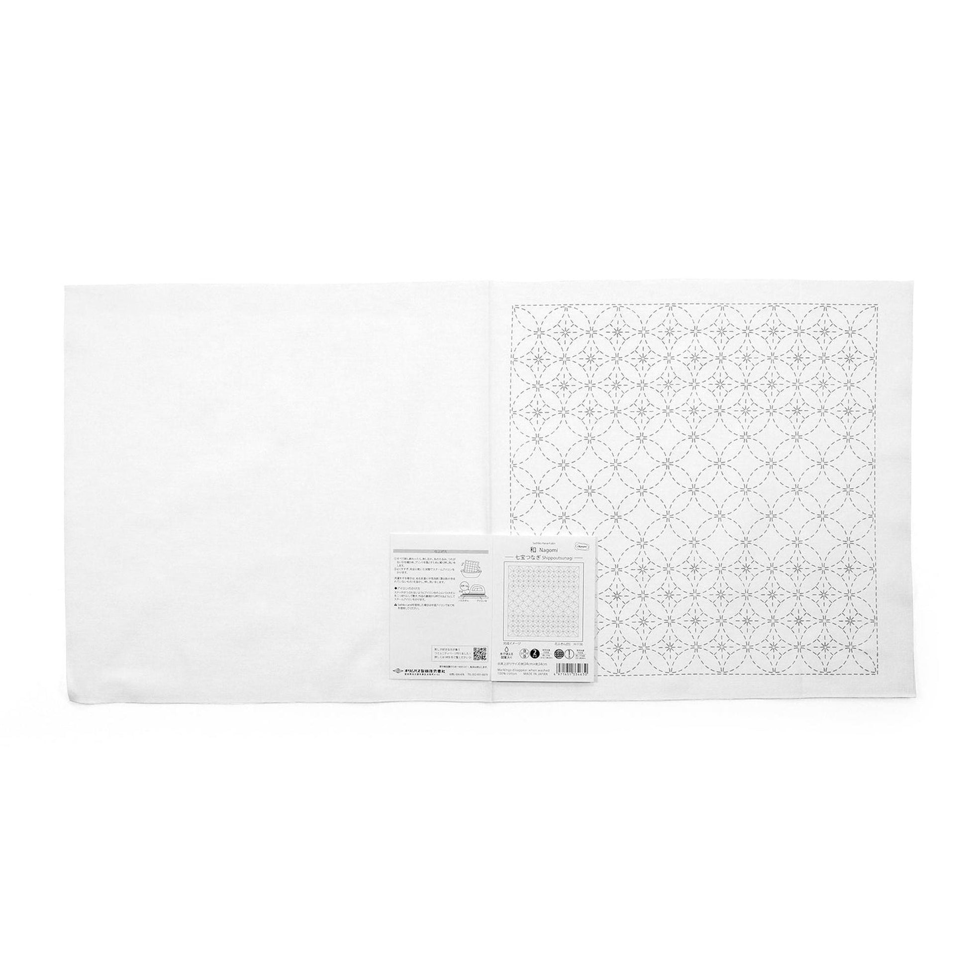 The image is a white square with a black and white pattern on it, placed next to a small white paper with text.