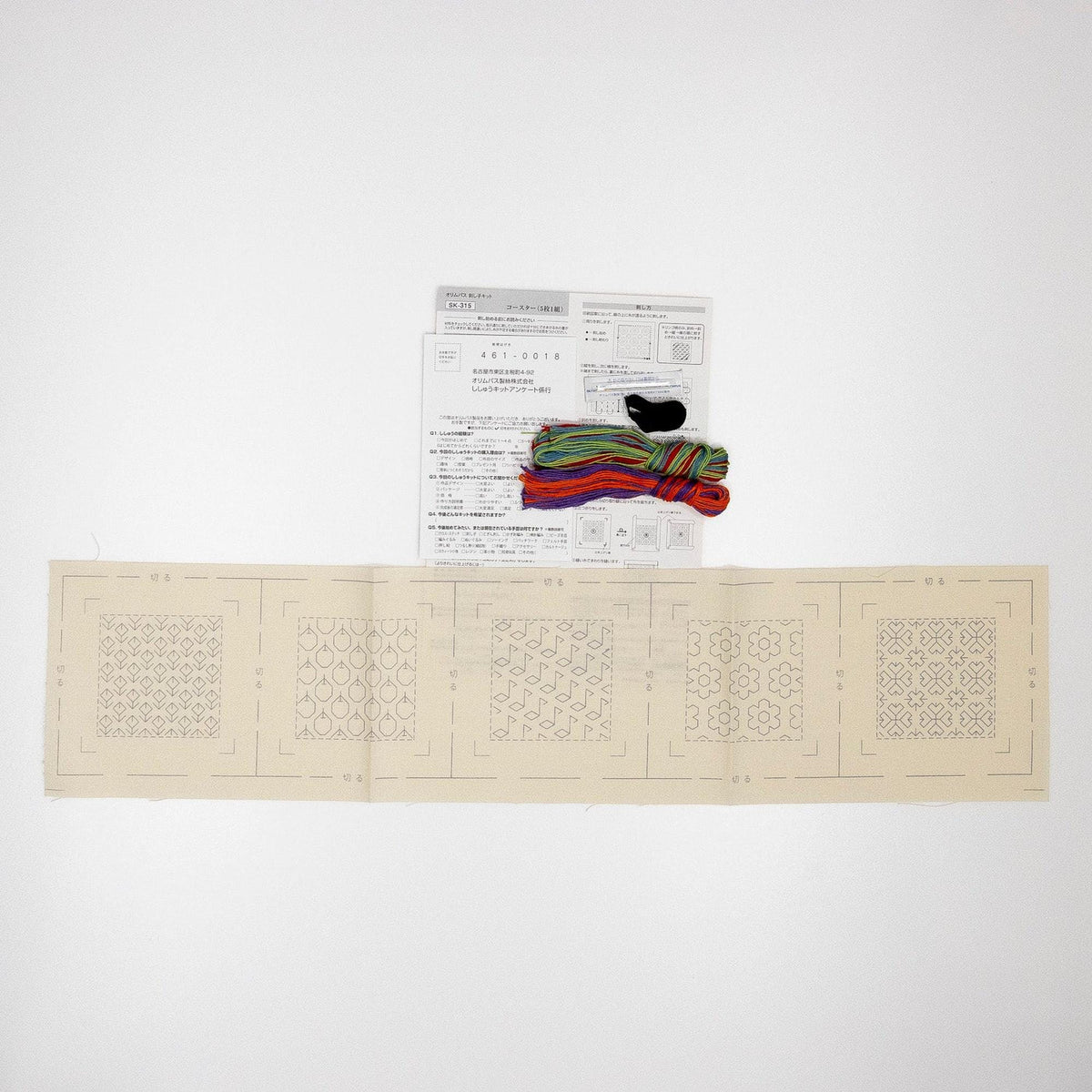 a sewing kit with instructions and colorful spools of thread, along with a beige paper with a pattern.