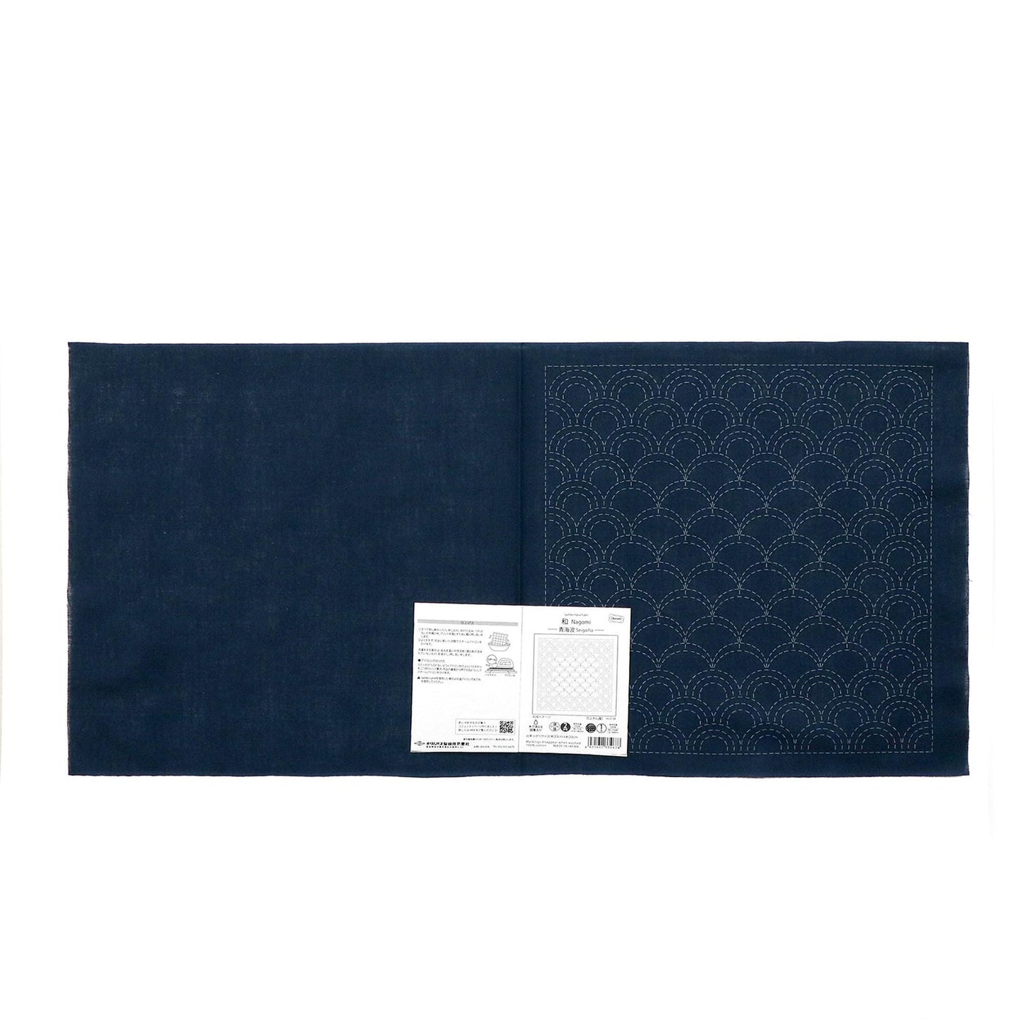 a dark blue fabric with a white pattern on it, and there is a small white paper with text next to it.