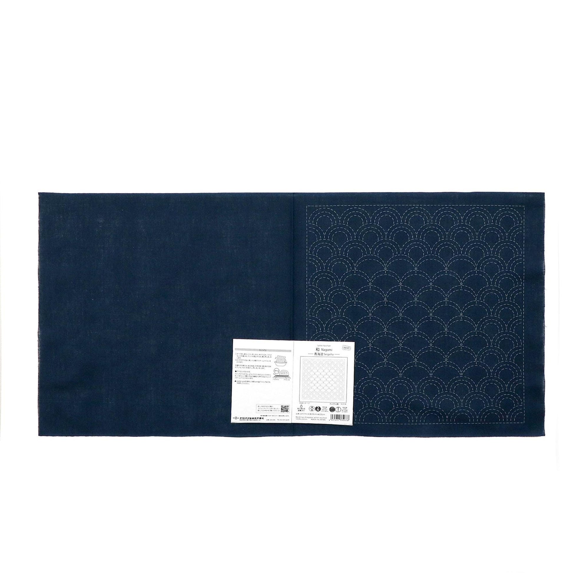 a dark blue fabric with a white pattern on it, and there is a small white paper with text next to it.