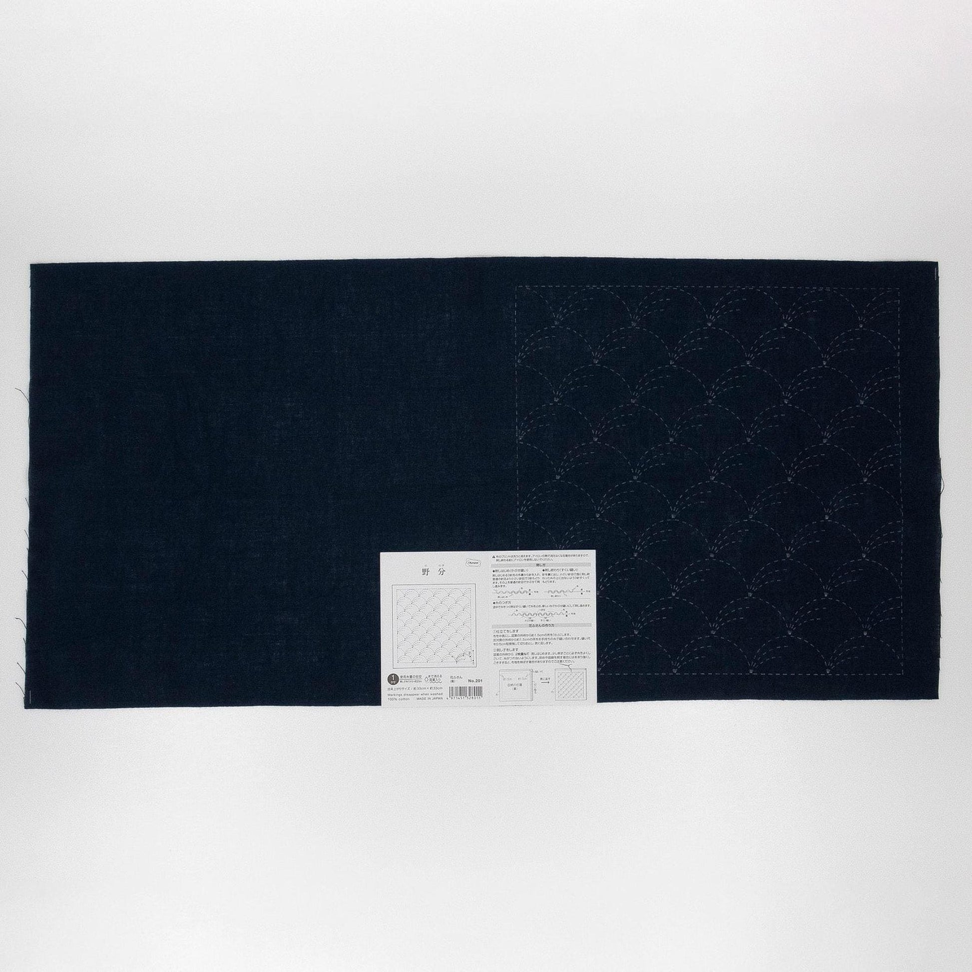 The image is a black fabric with a white label attached to it, which appears to be a sewing pattern or instructions.