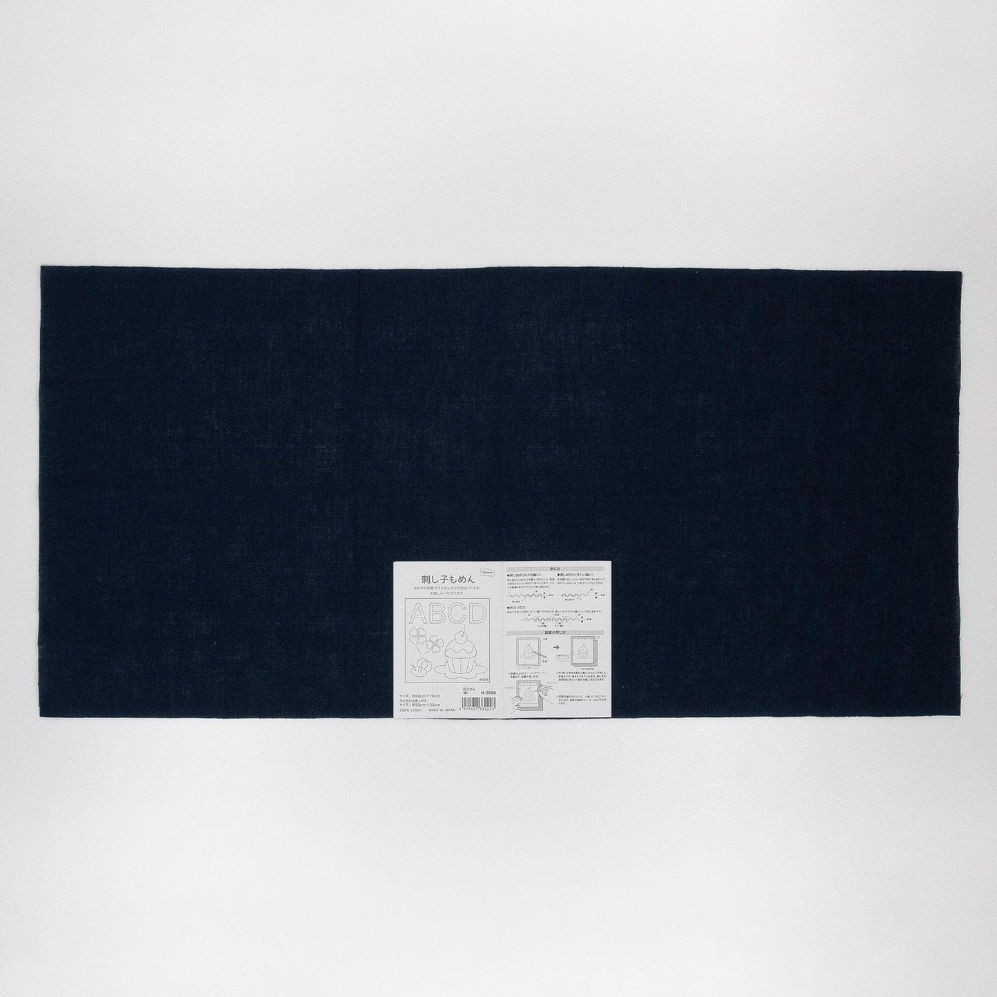 The image is a black rectangular fabric with a white label in the center, which appears to be a product label or instructions.