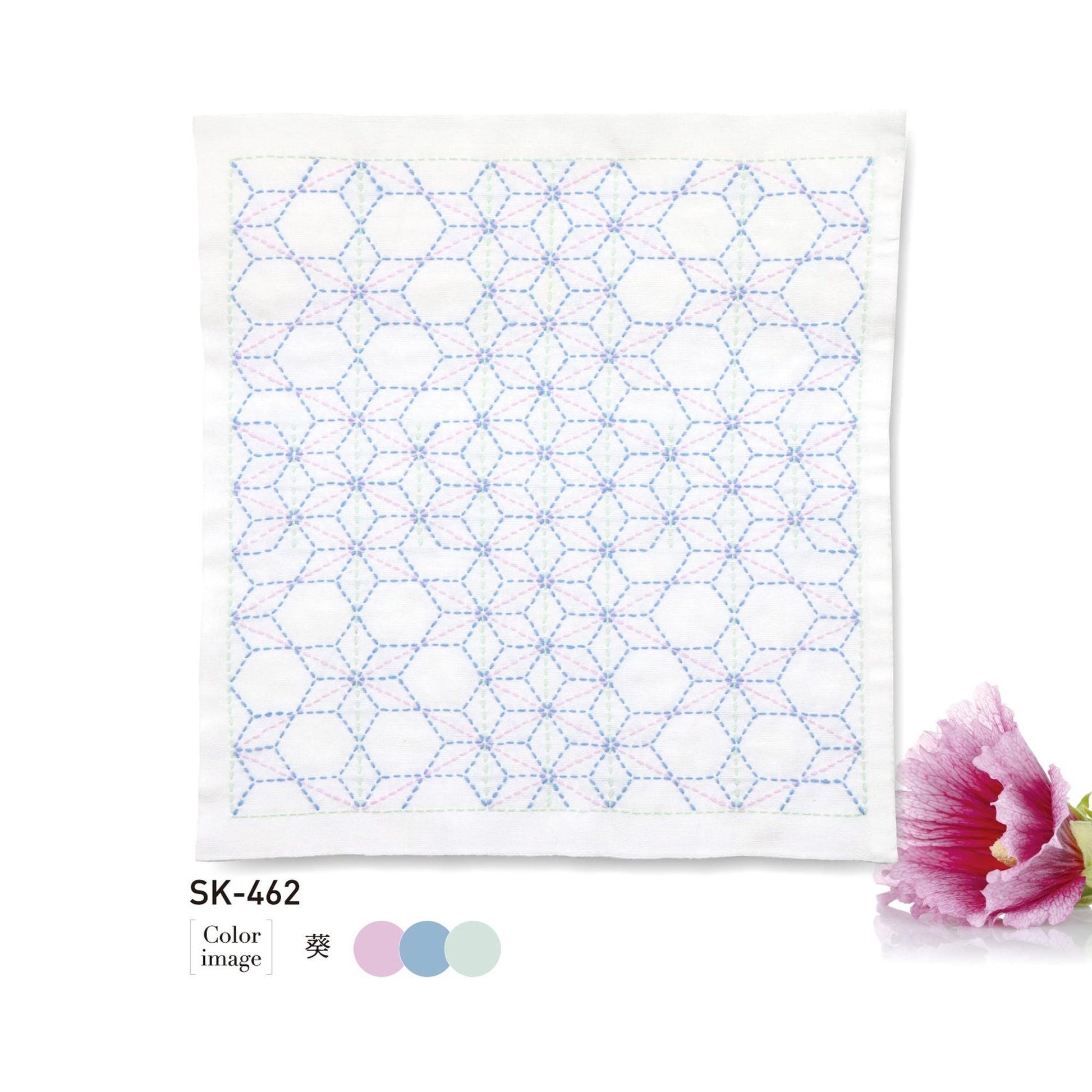 a square piece of fabric with a geometric pattern of hexagons and circles, and it is accompanied by a single pink flower.