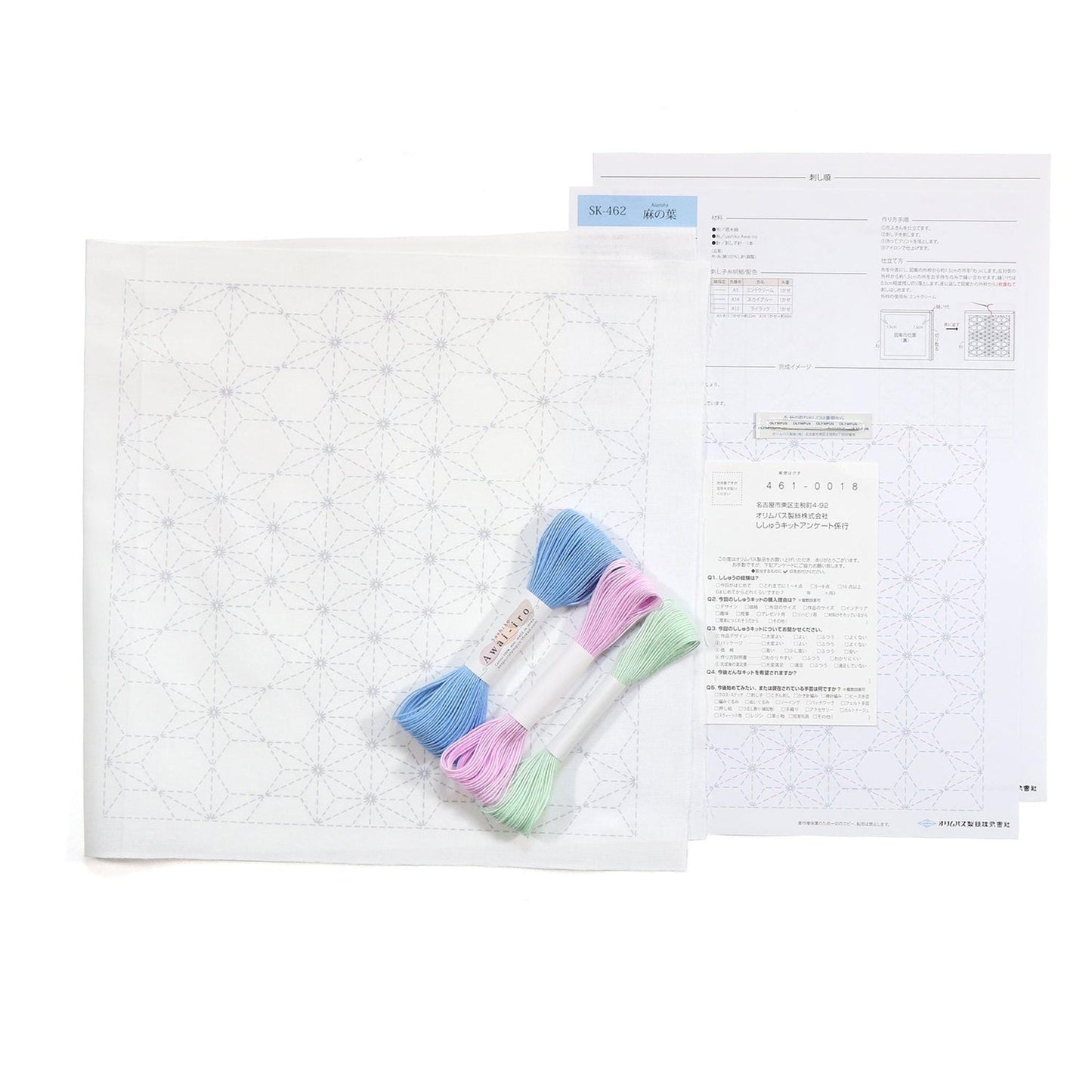a sewing kit with a white paper with a blue and white pattern, a pair of embroidery floss, and some instructions or information related to the kit.