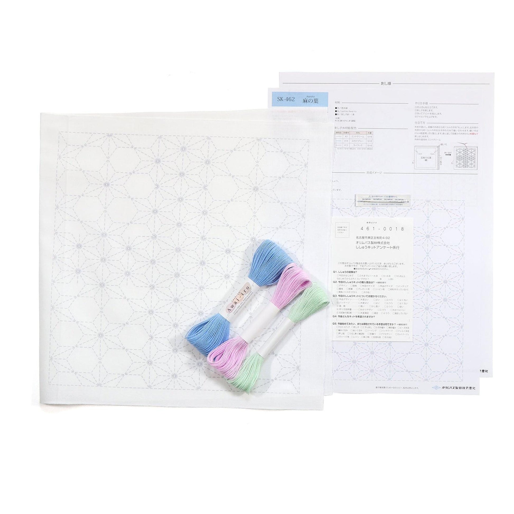 a sewing kit with a white paper with a blue and white pattern, a pair of embroidery floss, and some instructions or information related to the kit.