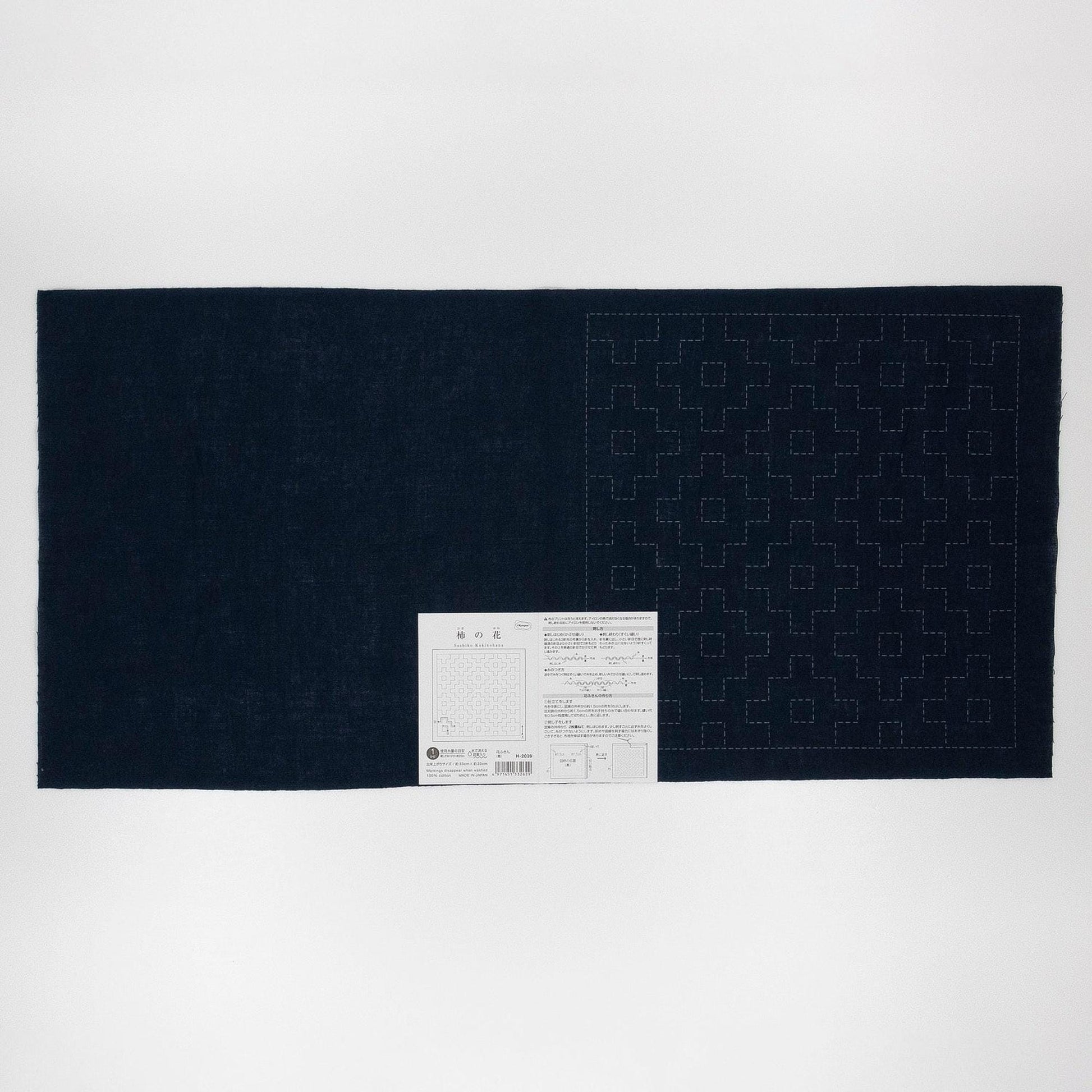 The image is a dark blue fabric with a white pattern on it, and there is a small white label with text attached to the bottom right corner of the fabric.