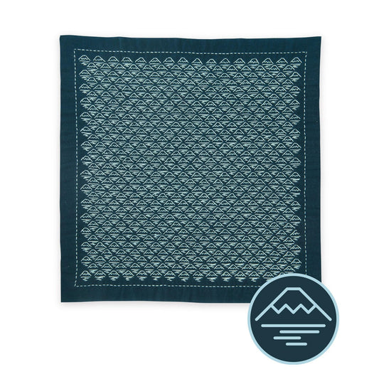 a square-shaped fabric with a repeating pattern of triangles in shades of blue and green.