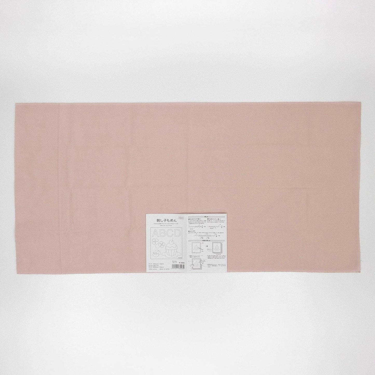 The image is a plain, light pink fabric or paper with a small label or text on it.
