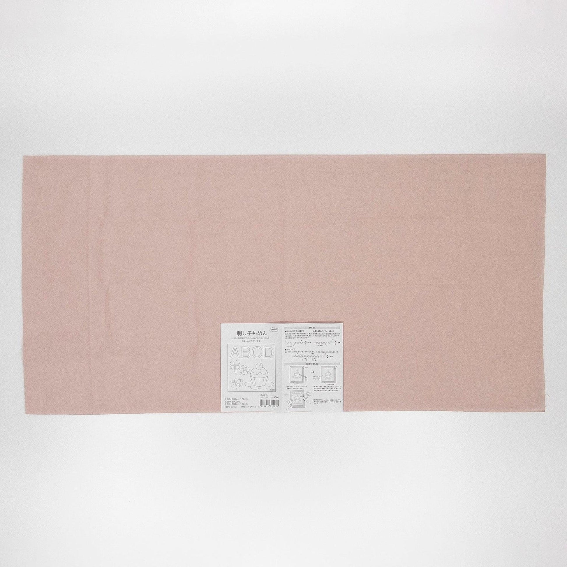 The image is a plain, light pink fabric or paper with a small label or text on it.