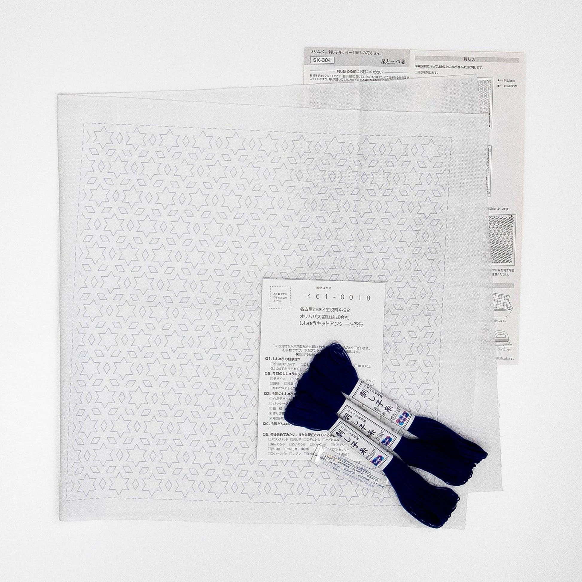 a white paper with a pattern of stars and dots, along with a set of blue embroidery floss and a white paper with text and diagrams.