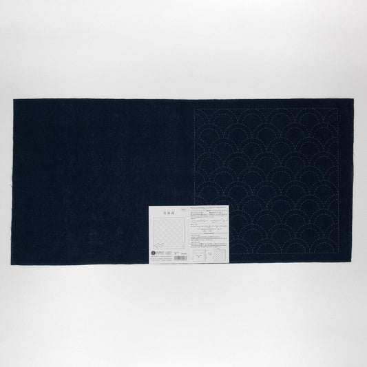 a dark blue fabric with a white pattern on it, placed on a white background. There is a small white label or instruction sheet attached to the fabric, but the text is not legible.