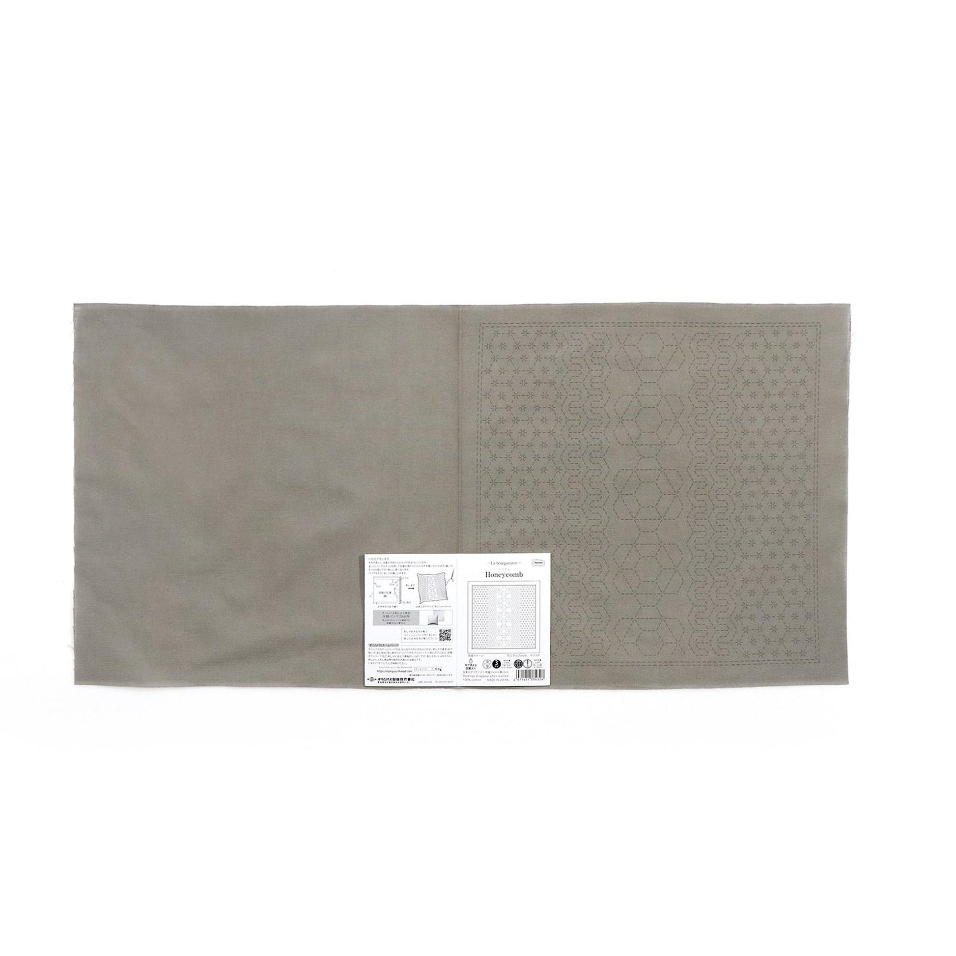 a gray fabric with a patterned design on one side, and a small white label with text on the other side.