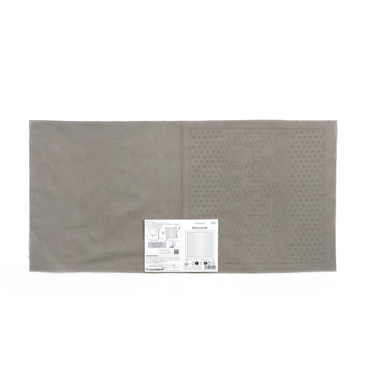 a gray fabric with a patterned design on one side, and a small white label with text on the other side.
