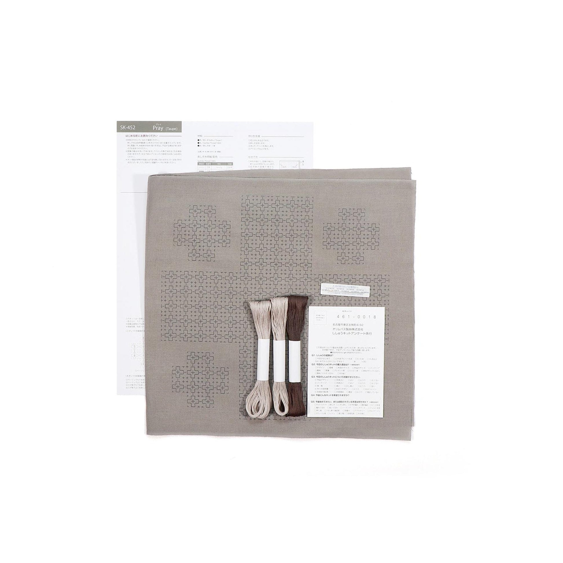 a sewing kit with various items, including a piece of paper with instructions, thread, and a pattern.