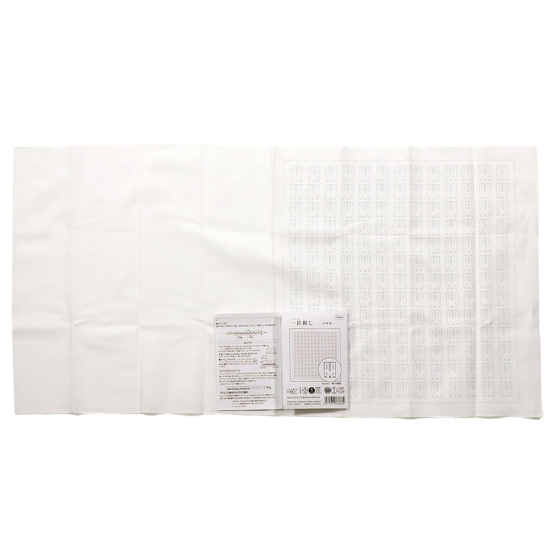 a white cloth with a grid pattern, and there is a small white paper with text and a barcode next to it.