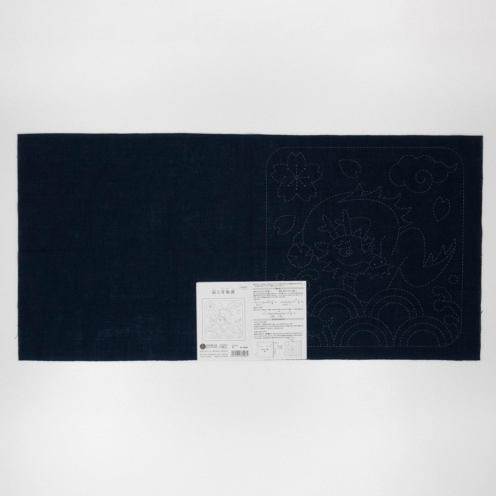The image is a black fabric with a white label attached to it, which appears to be a sewing pattern or instructions.