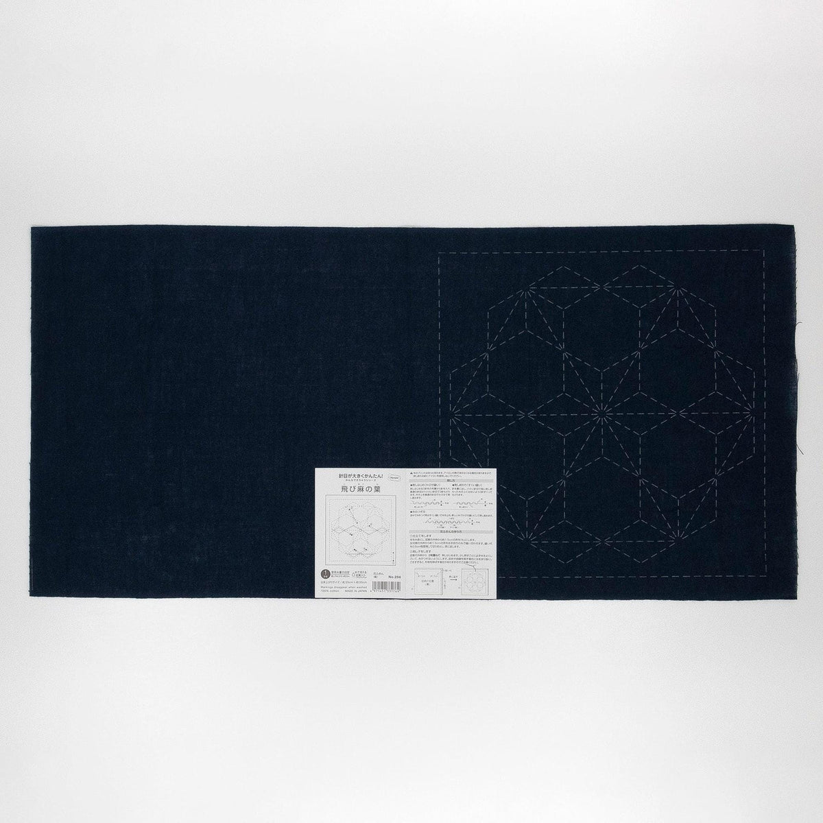 a dark blue fabric with a white geometric pattern on it, along with a small white label or instruction sheet attached to the fabric.