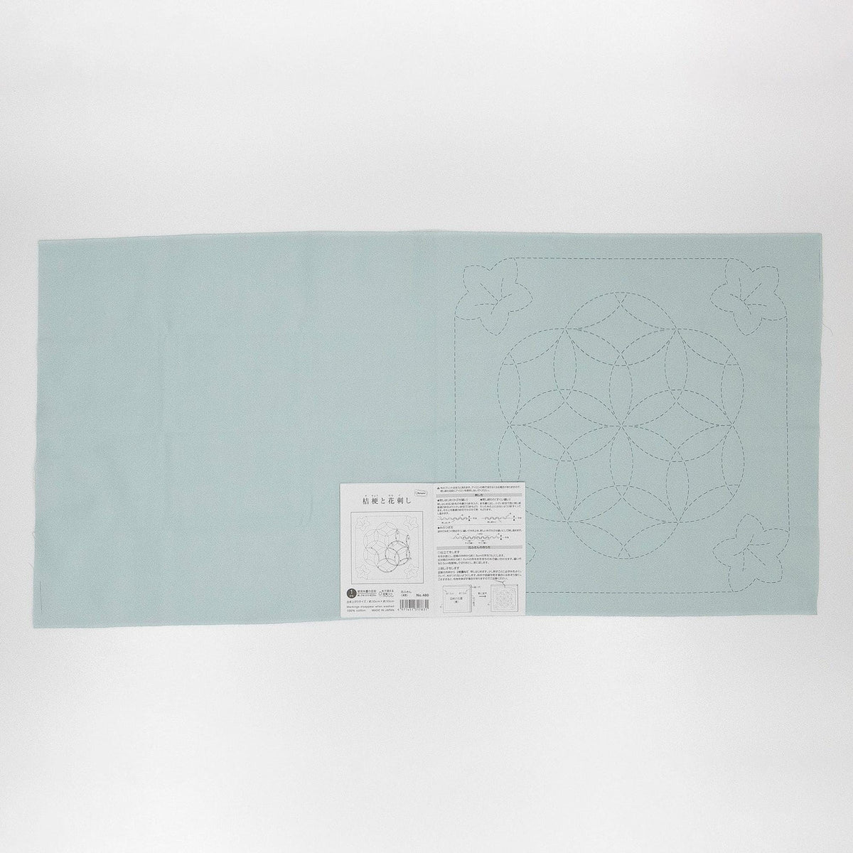 The image is a light blue fabric with a geometric pattern on it, and there is a label with instructions or information about the fabric.