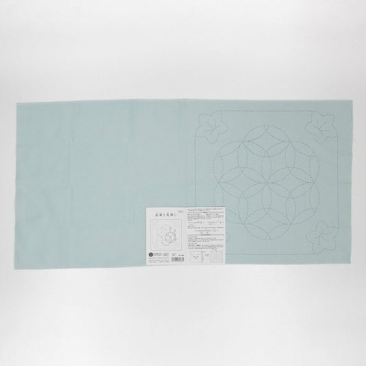 The image is a light blue fabric with a geometric pattern on it, and there is a label with instructions or information about the fabric.