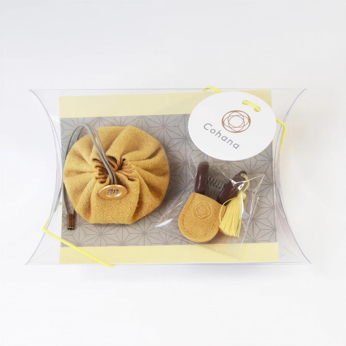 A small, round, yellow pouch with a metal clasp and a small tassel is placed on a clear, curved surface.