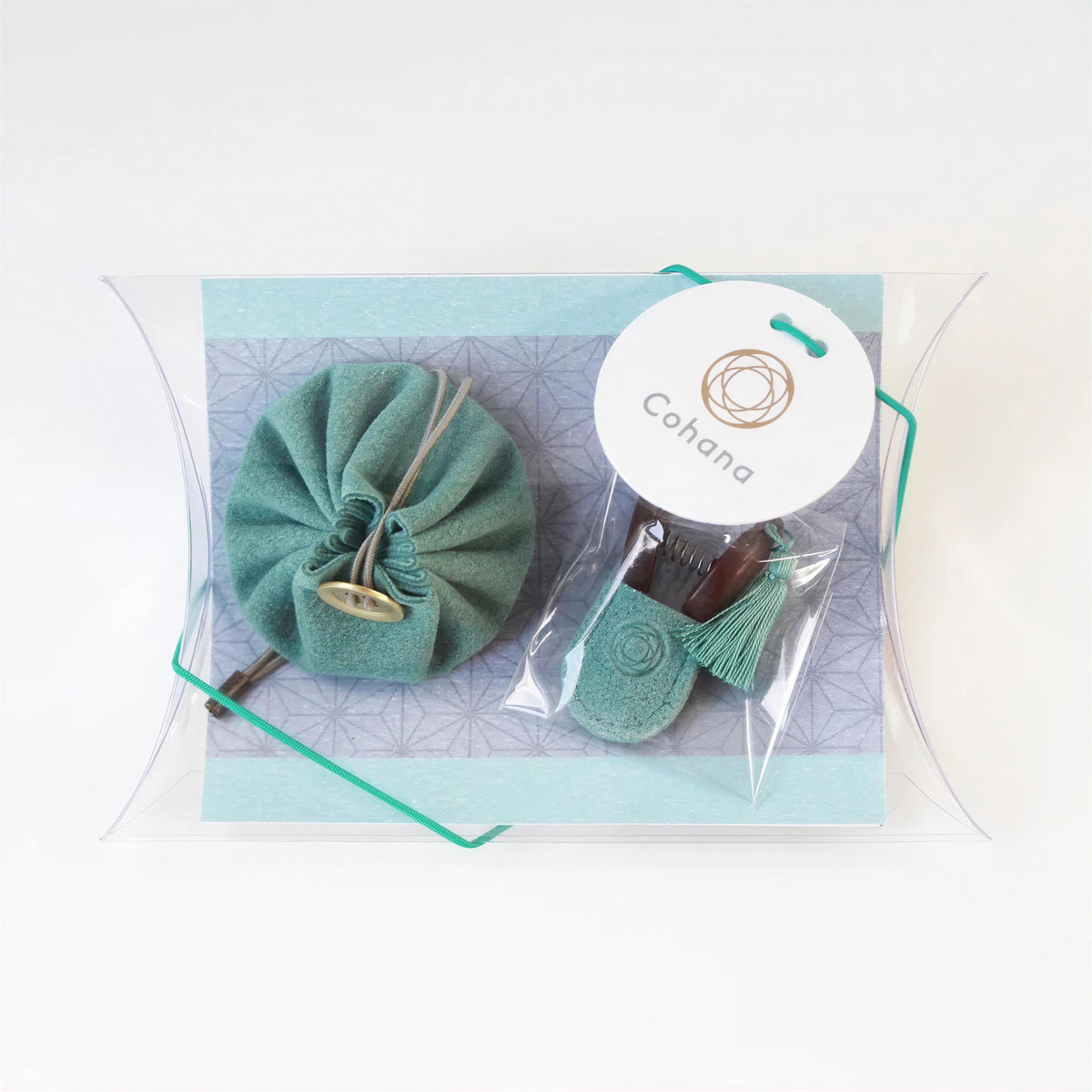 A package containing a green cloth bag, a small tassel, and a keychain, with a white circular tag that reads "Cohana".
