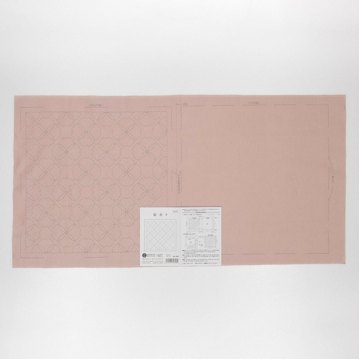 a pink fabric with a white pattern on it, along with a small white paper with text and diagrams on it.