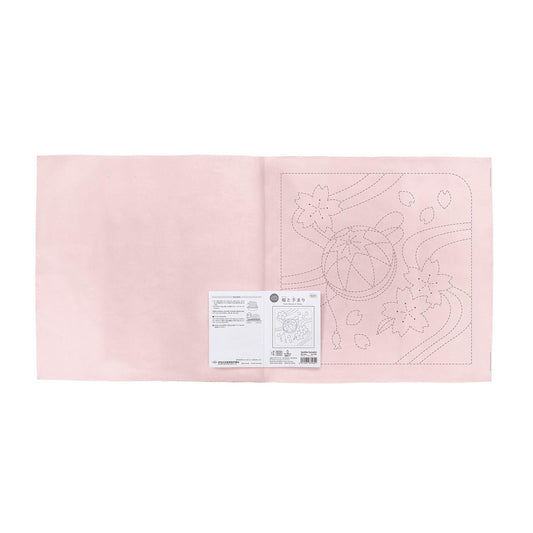 The image is a pink fabric with a printed design on it, and there is a small white label with text next to it.