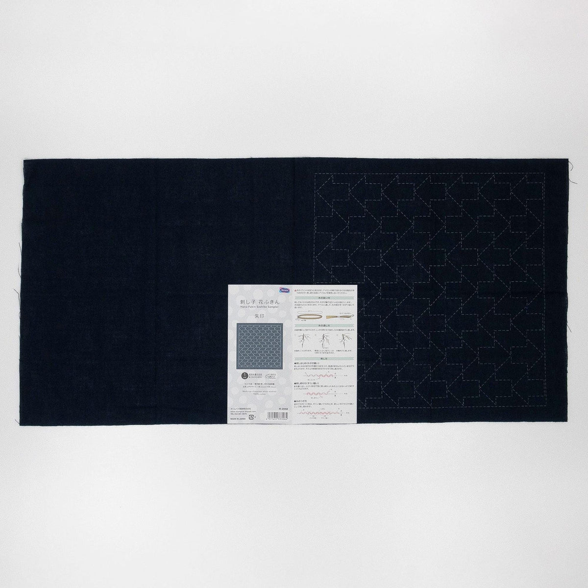 The image is a black fabric with a pattern on it, and there is a piece of paper with instructions or information about the fabric.