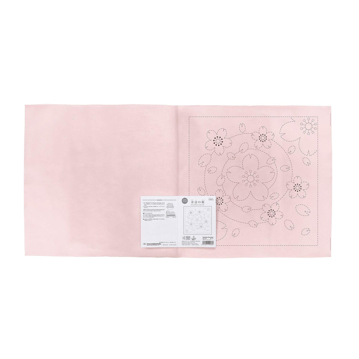 a pink fabric with a floral pattern and a small white label with text and diagrams.