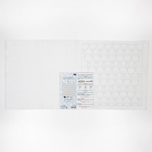 The image is a white sheet of paper with a pattern or design on it, along with a small blue and white label or booklet that appears to contain instructions or information related to the pattern or design.