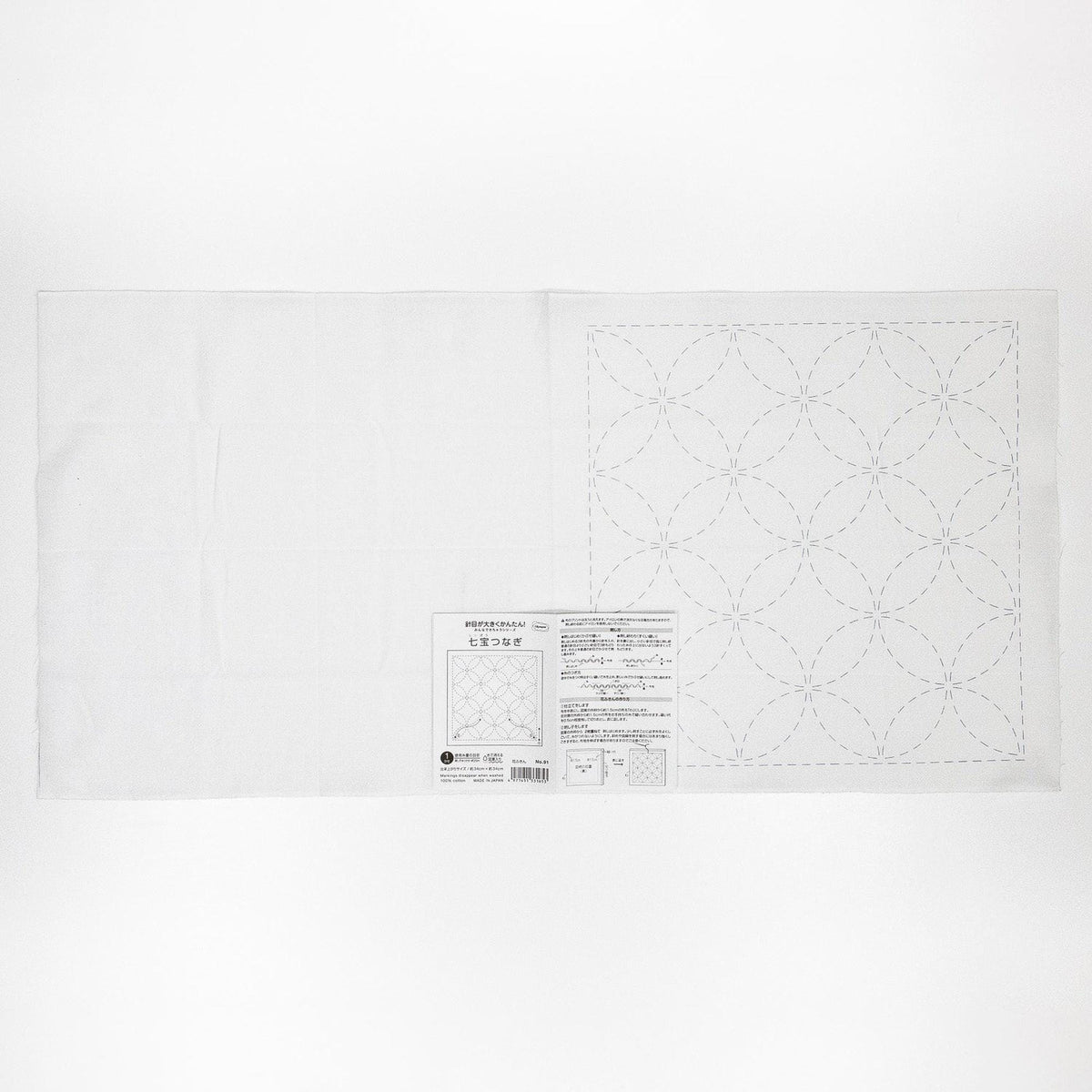 The image is a white fabric with a detailed pattern of circles and lines, along with some text and a barcode.