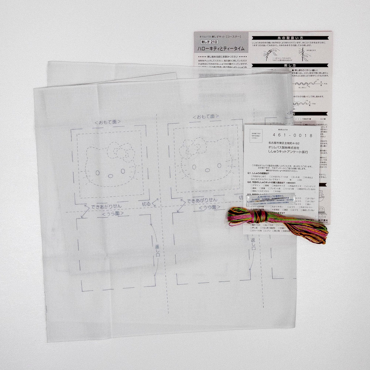a sheet of paper with a drawing of a Hello Kitty character, along with some instructions or information related to the drawing. There is also a spool of thread and a piece of paper with text, which appears to be instructions or guidelines for the Hello Kitty drawing.