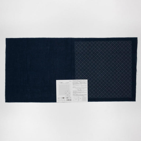 a dark blue fabric with a white pattern on it, placed on a white background. There is a small white label with text next to the fabric.
