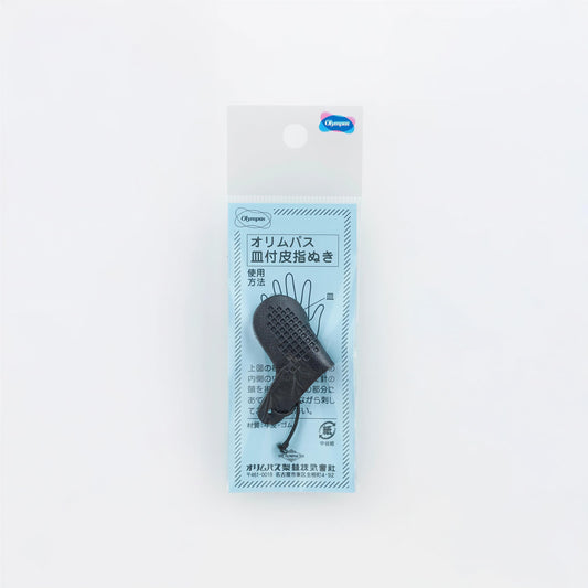 A package containing a black object, possibly a tool or accessory, with Japanese text and a blue label.