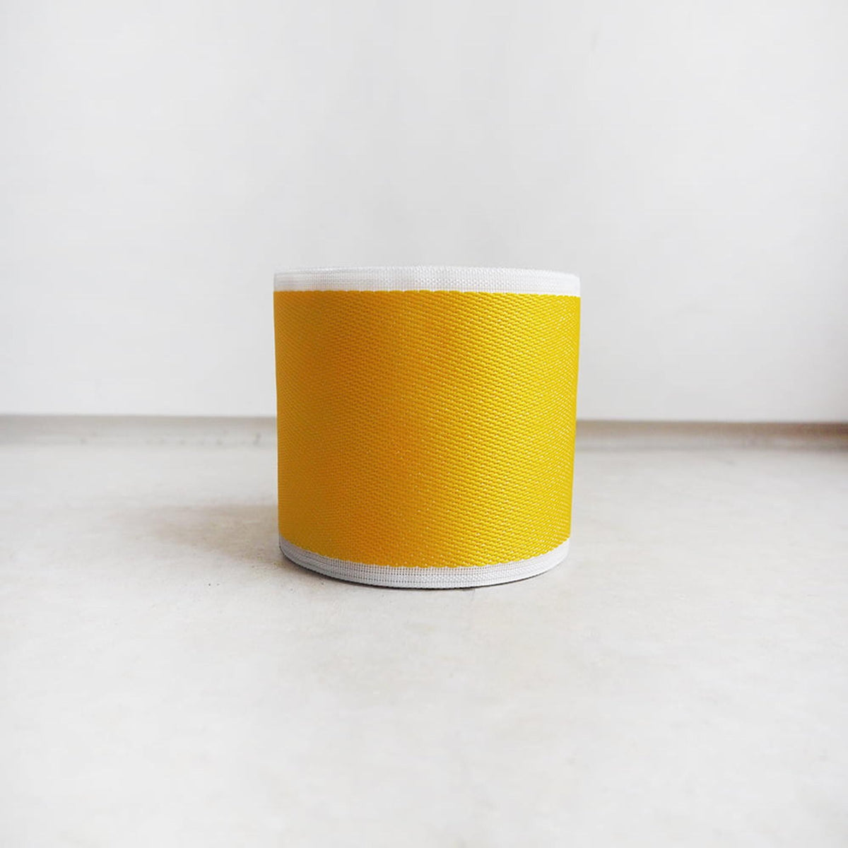A single yellow object, possibly a container or object, is centered in the image against a plain white background.