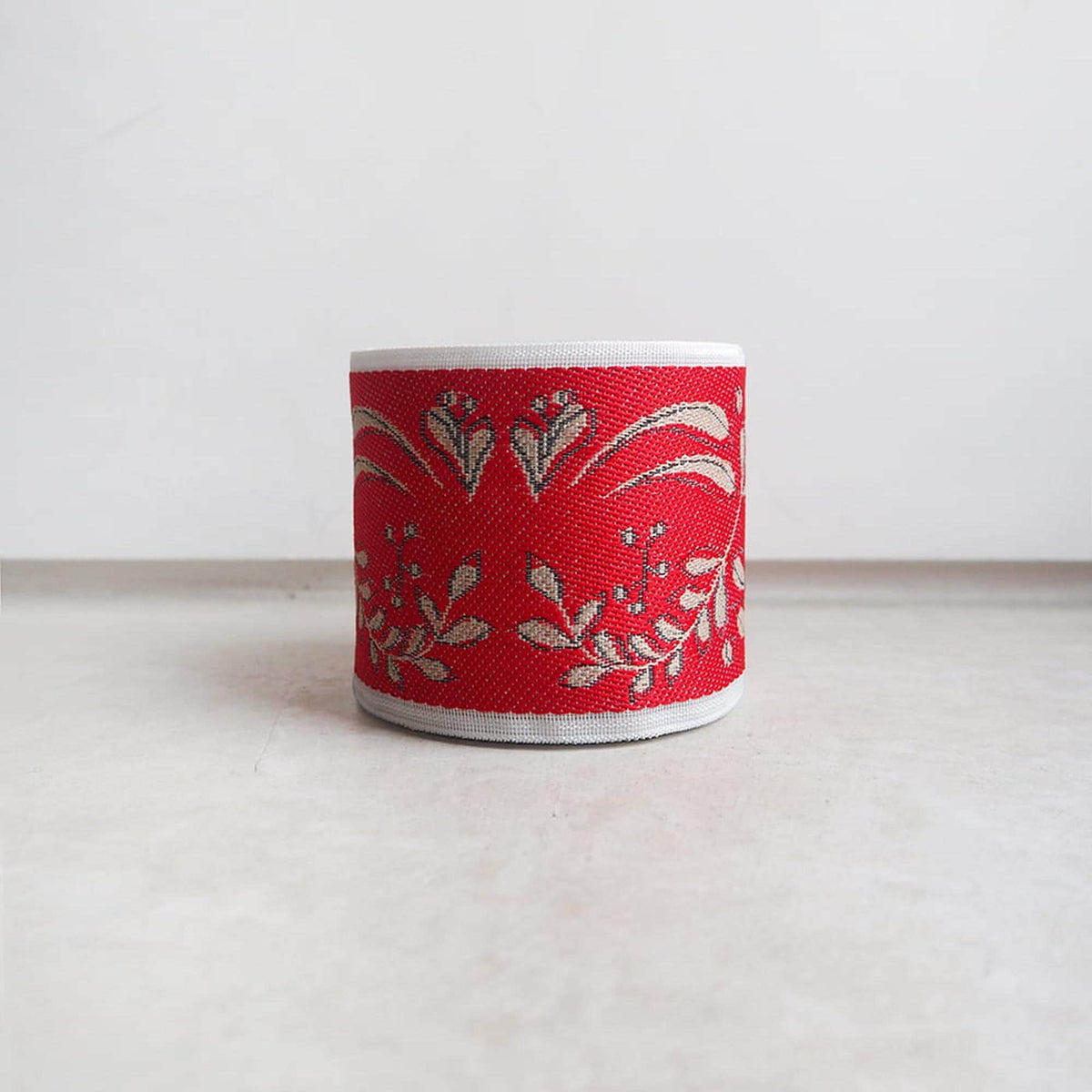 A red and white decorative band with a floral pattern is displayed on a white surface.