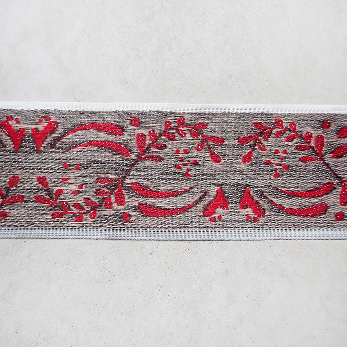 a decorative border with a repeating pattern of red flowers and leaves on a gray background.