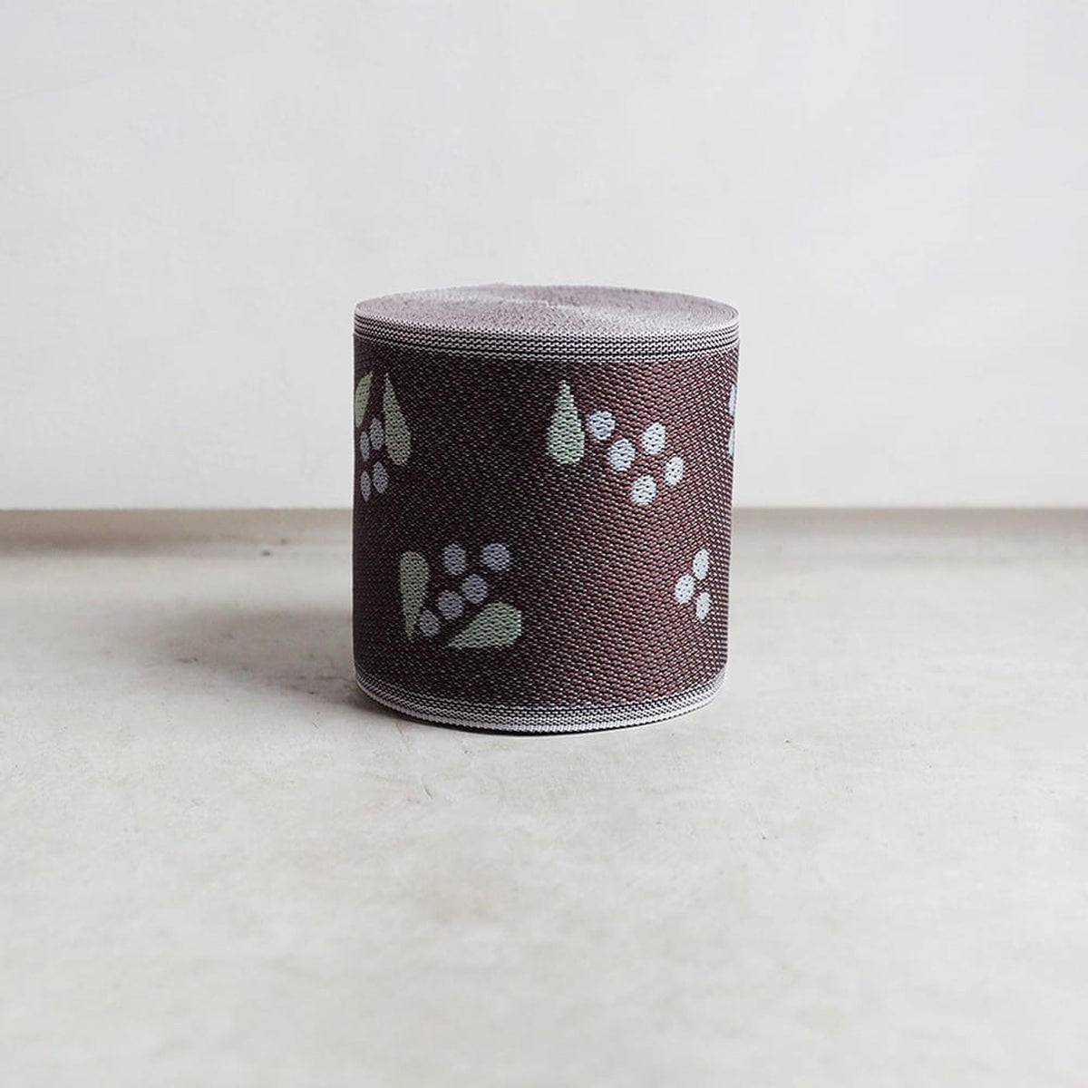 A cylindrical object with a brown and white patterned design, sitting on a plain surface.