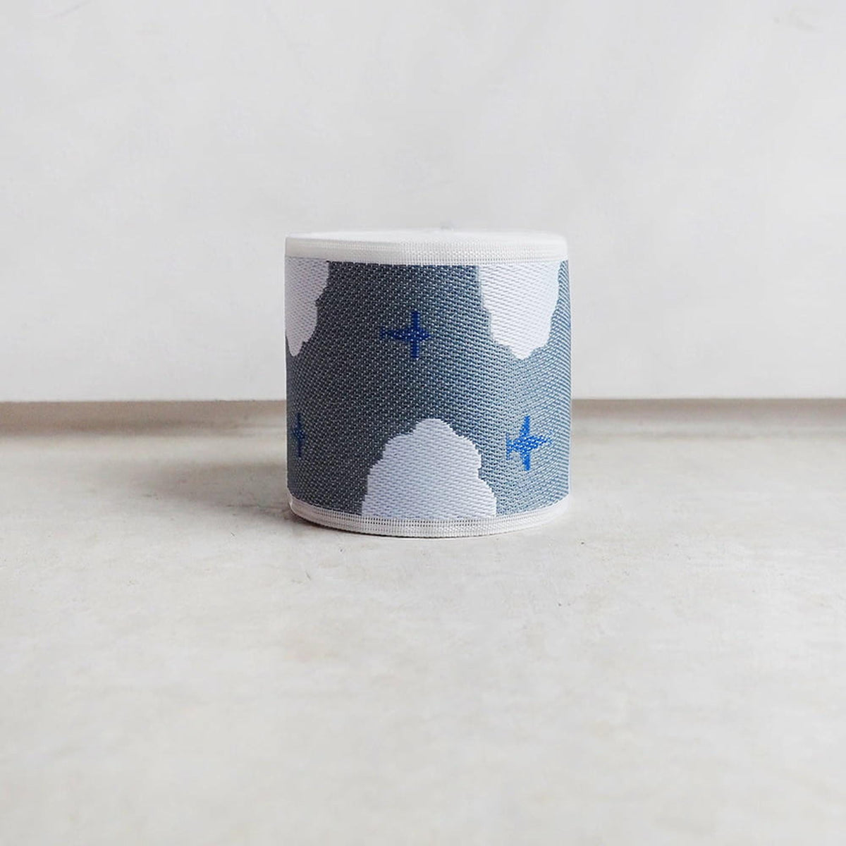 A cylindrical object with a cloud-like pattern in shades of blue and white, featuring small blue dots resembling stars.