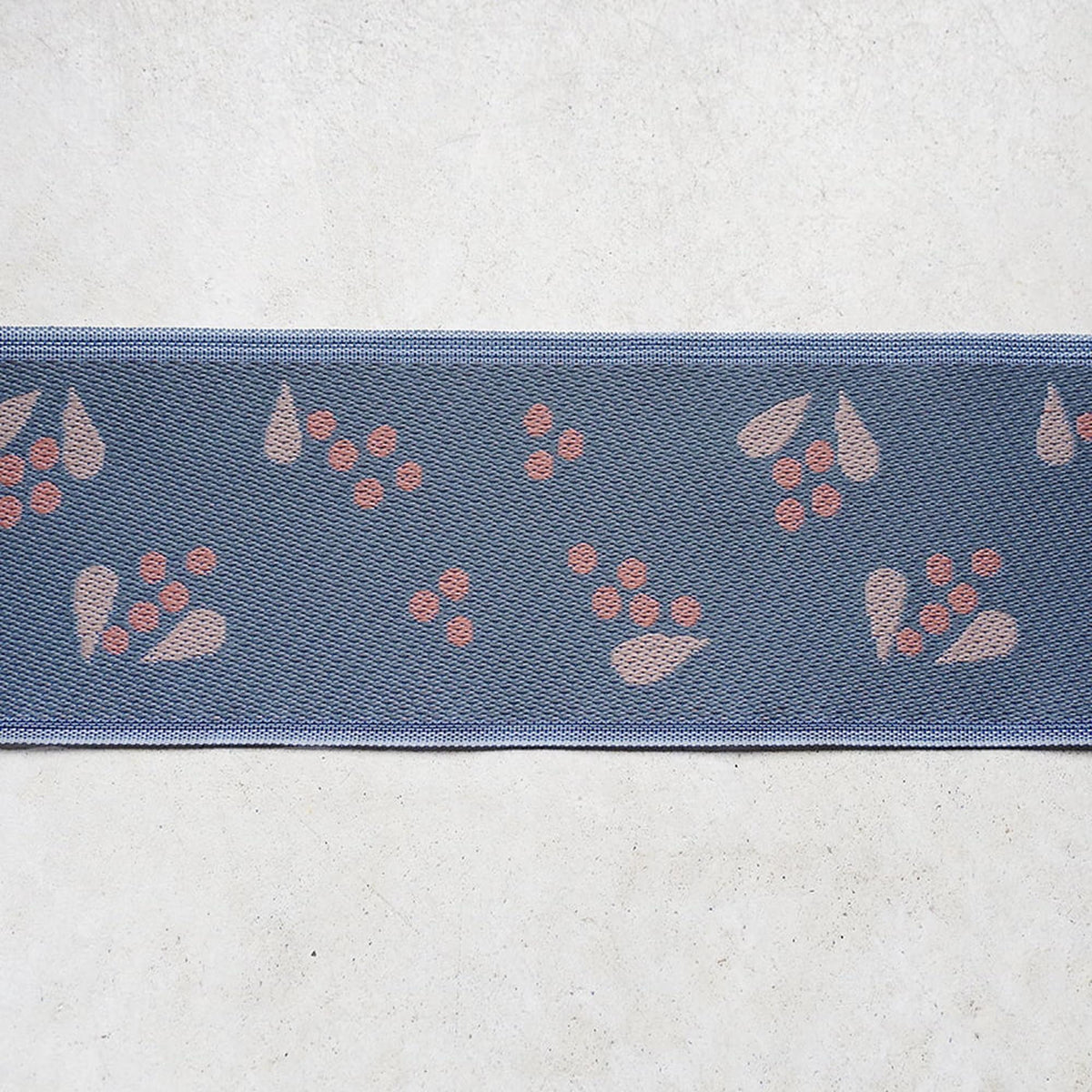 a blue fabric with a repeating pattern of pink flowers or leaves on it.