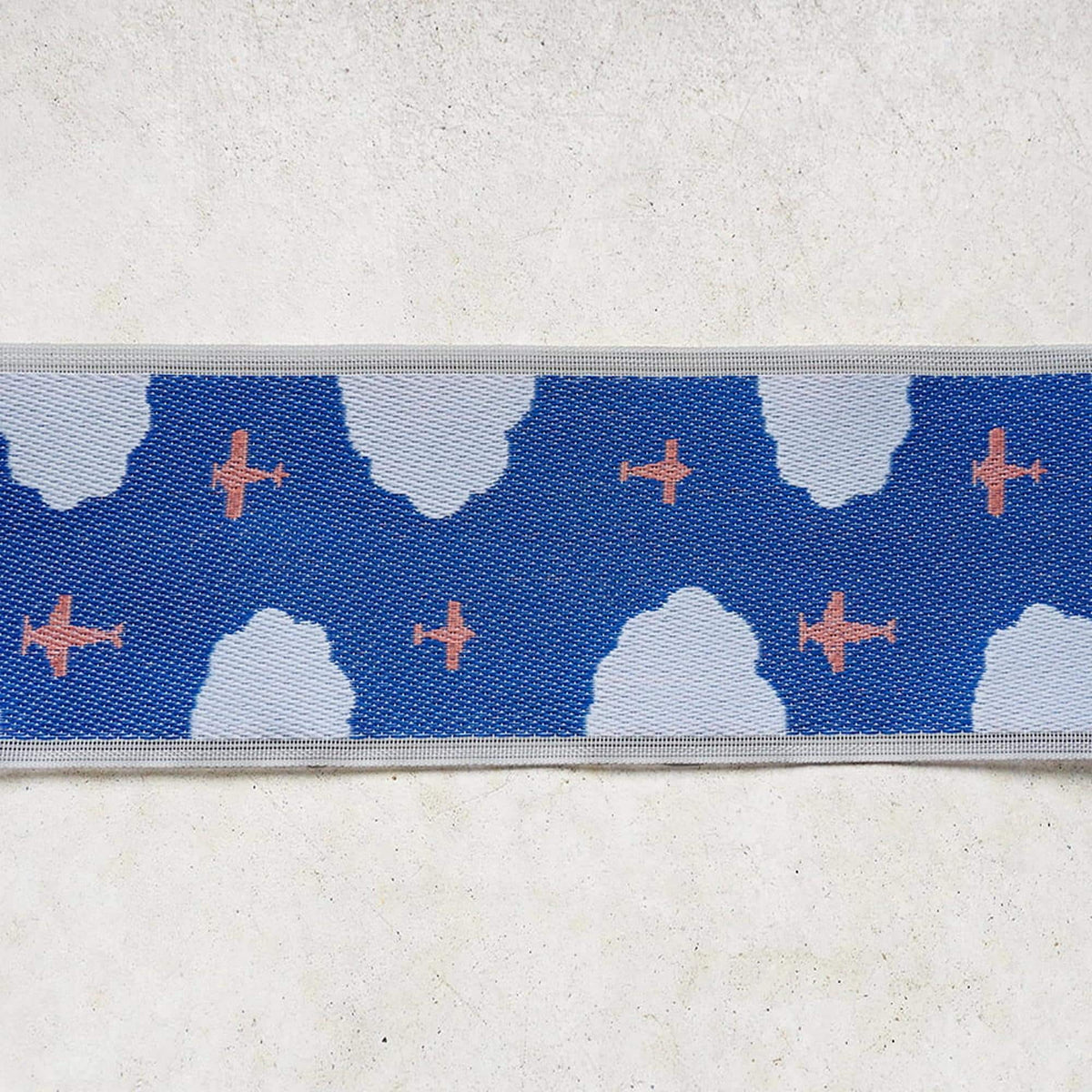 a blue background with a repeating pattern of white clouds and orange airplanes.