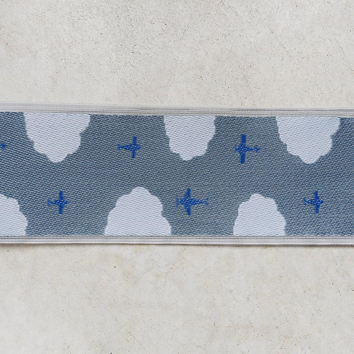 a repeating pattern of blue airplanes and clouds on a gray background.