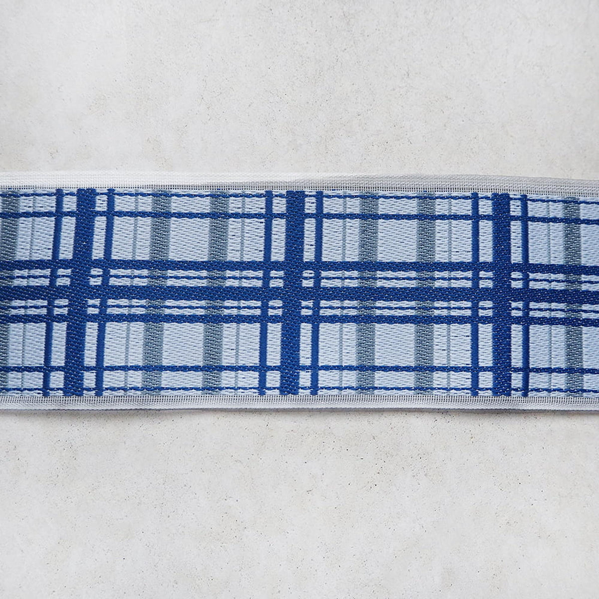 A close-up view of a blue and white plaid pattern on a white surface.