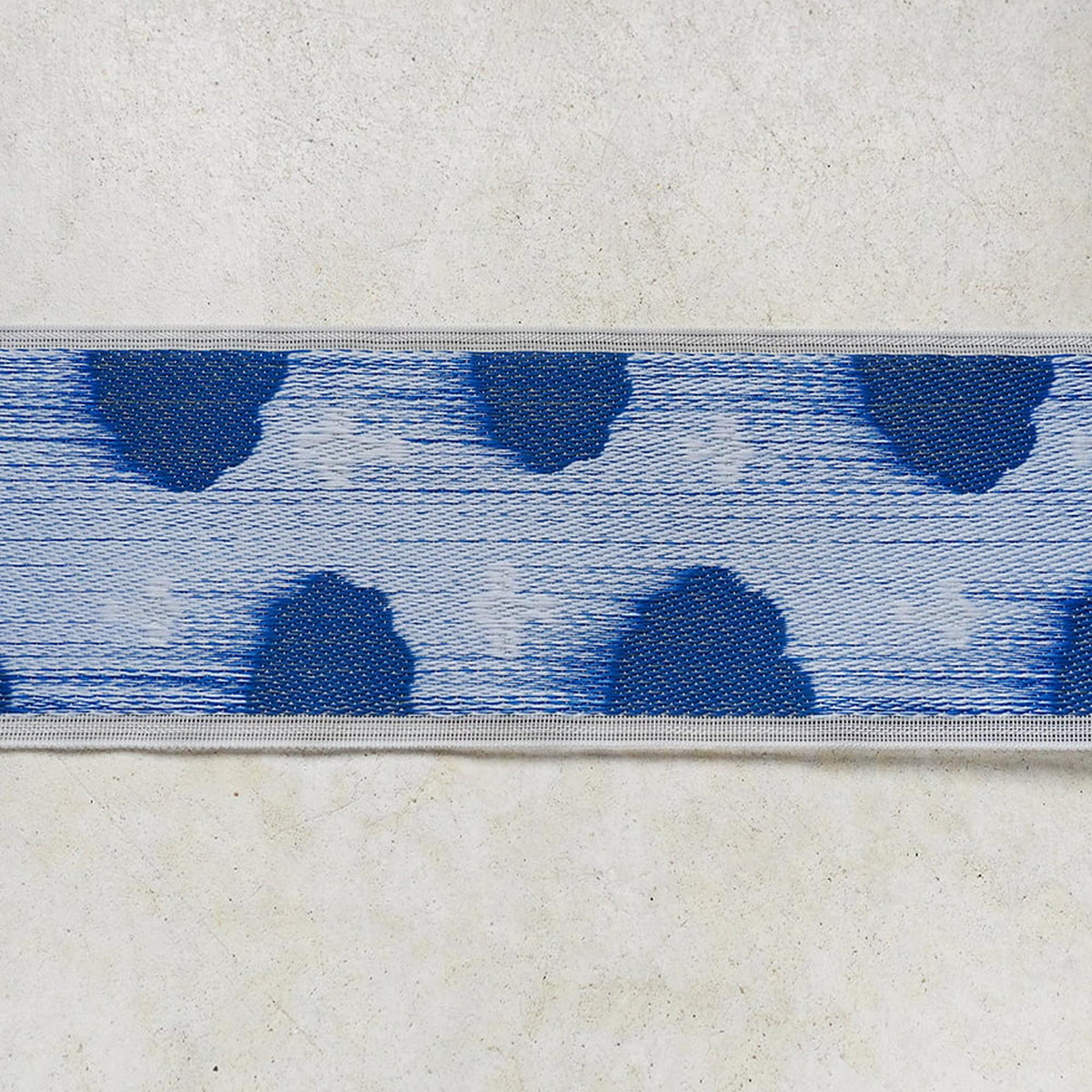a close-up view of a blue and white patterned fabric or textile, with a repeating design of blue hearts or circles on a white background.