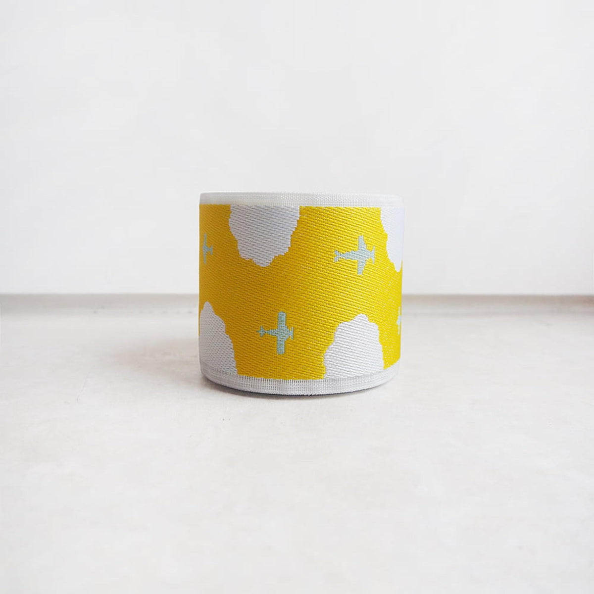 A yellow and white striped object with a cloud pattern on it, sitting on a white surface.