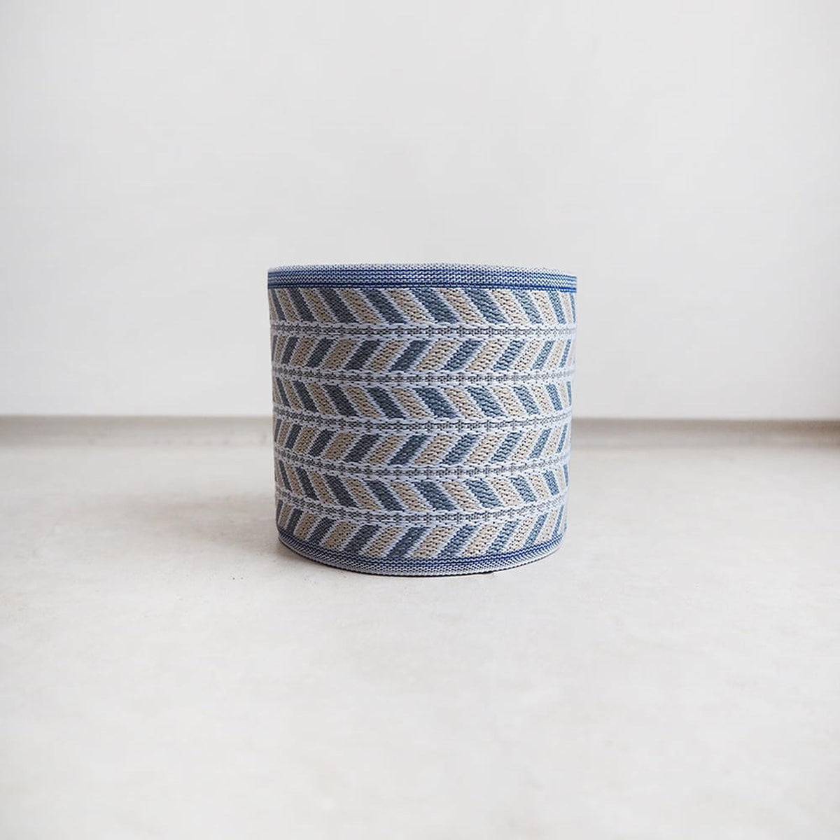 A cylindrical object with a blue and white geometric pattern, sitting on a white surface.