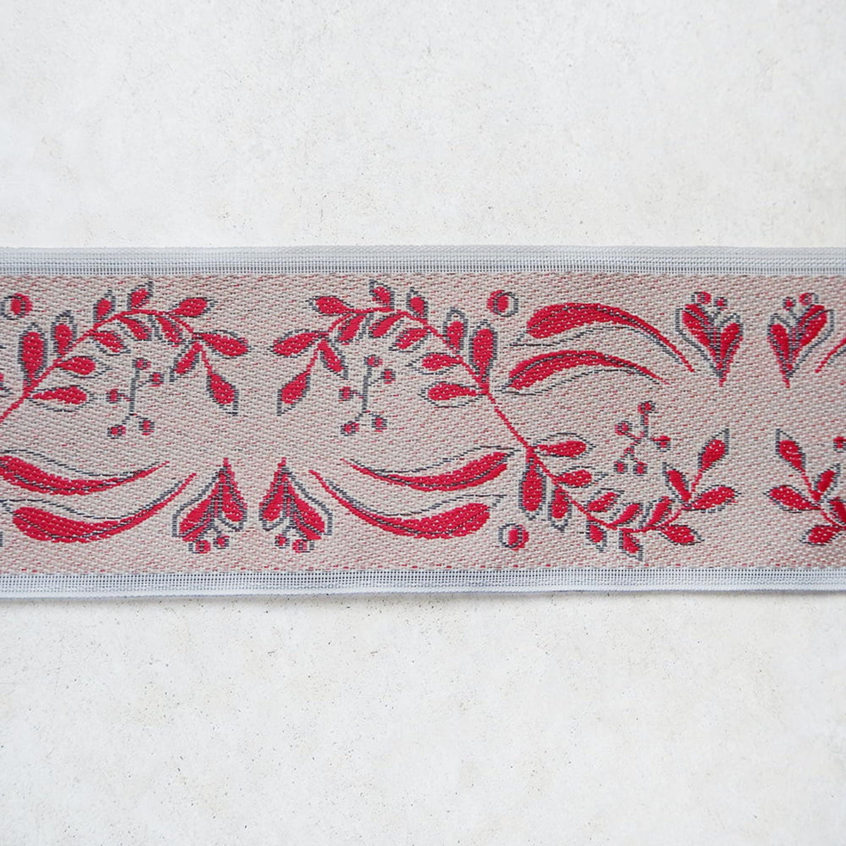 a decorative border with a repeating pattern of red leaves and flowers on a beige background.