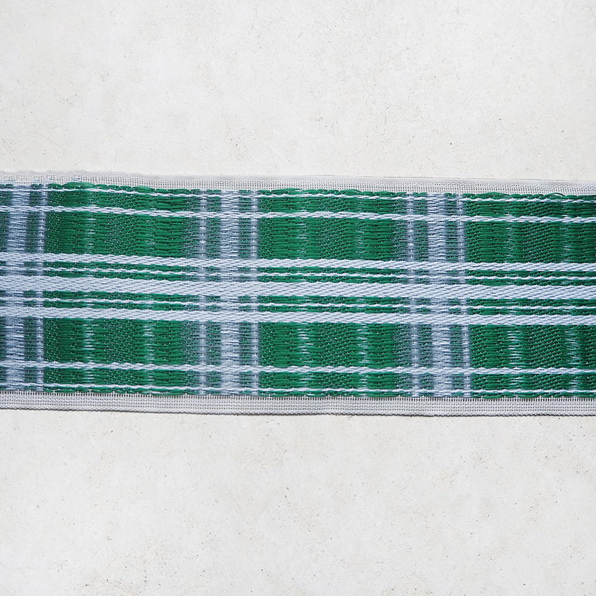 A close-up view of a green and white plaid fabric, with the fabric's pattern and color variations clearly visible.