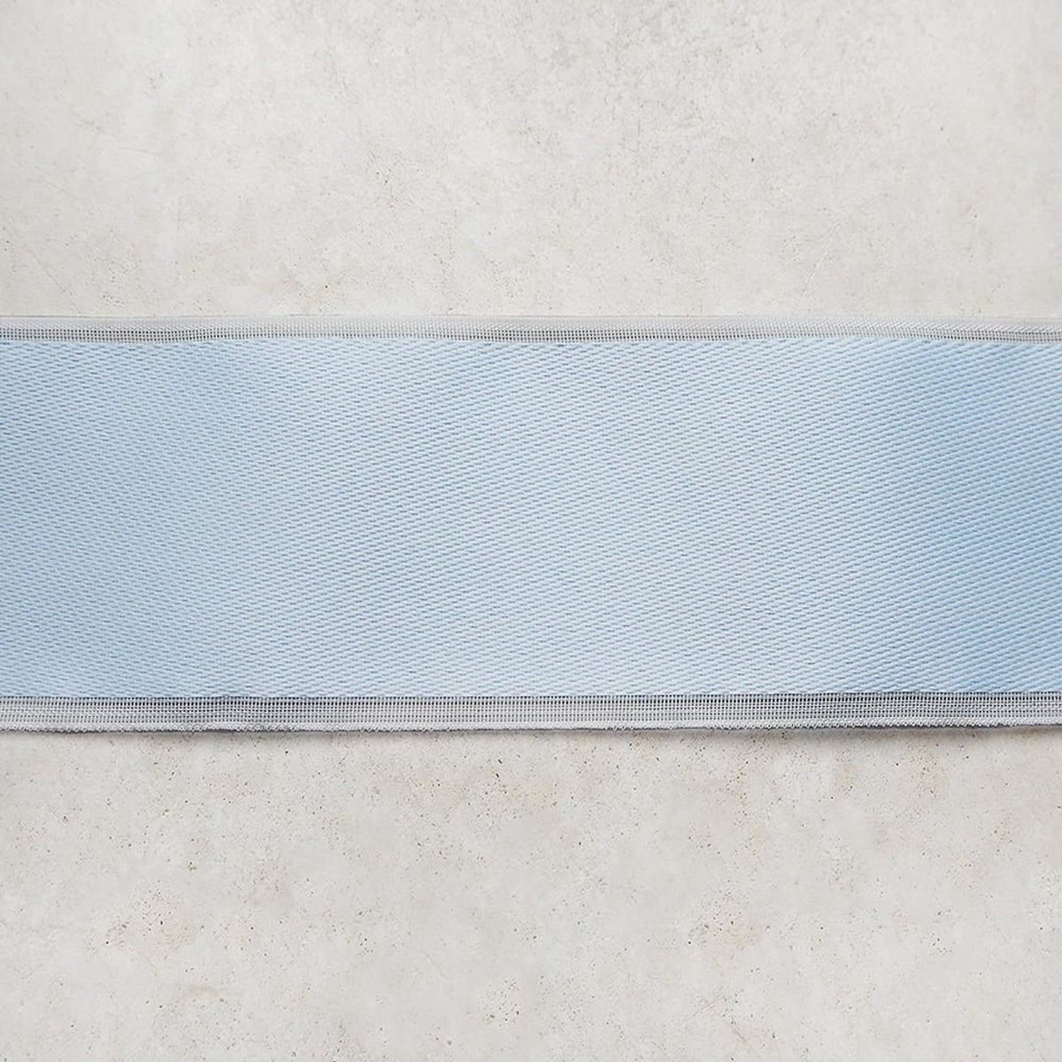 A close-up view of a light blue fabric or ribbon, with a textured surface.